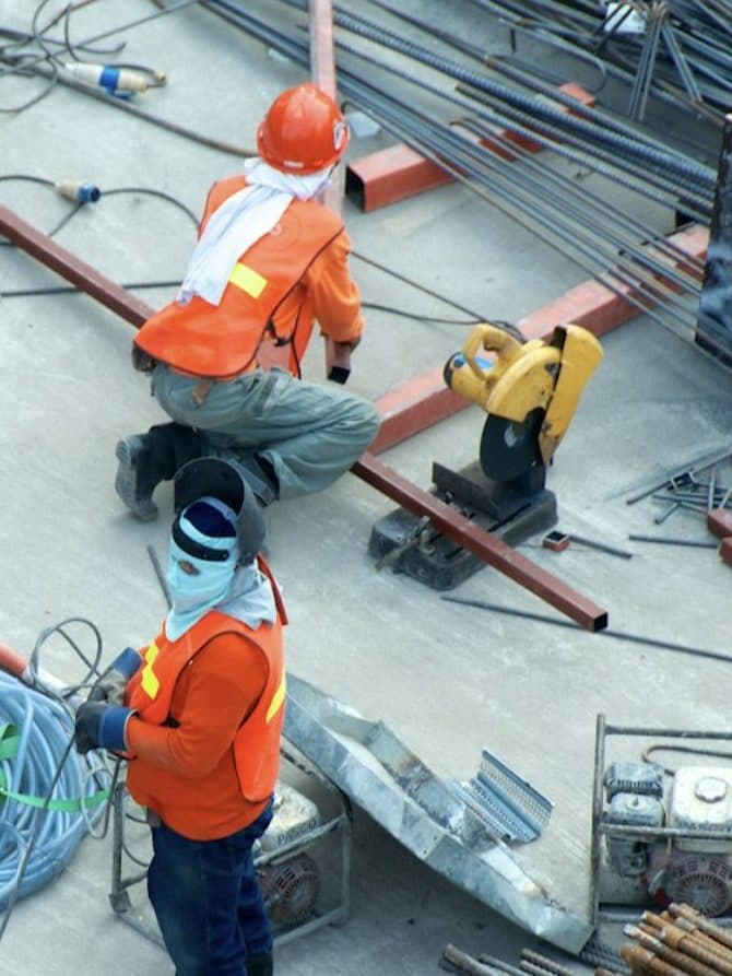 Construction workers in hard hats and high-visibility vests on a building site.